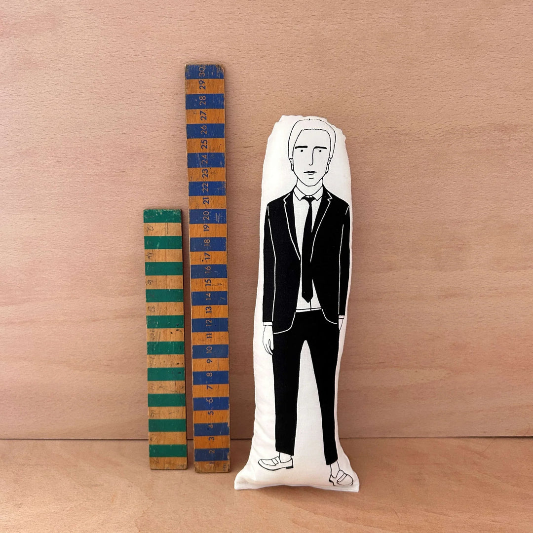 Screen printed doll cushion of Paul Weller next to two wooden rulers and a wooden background