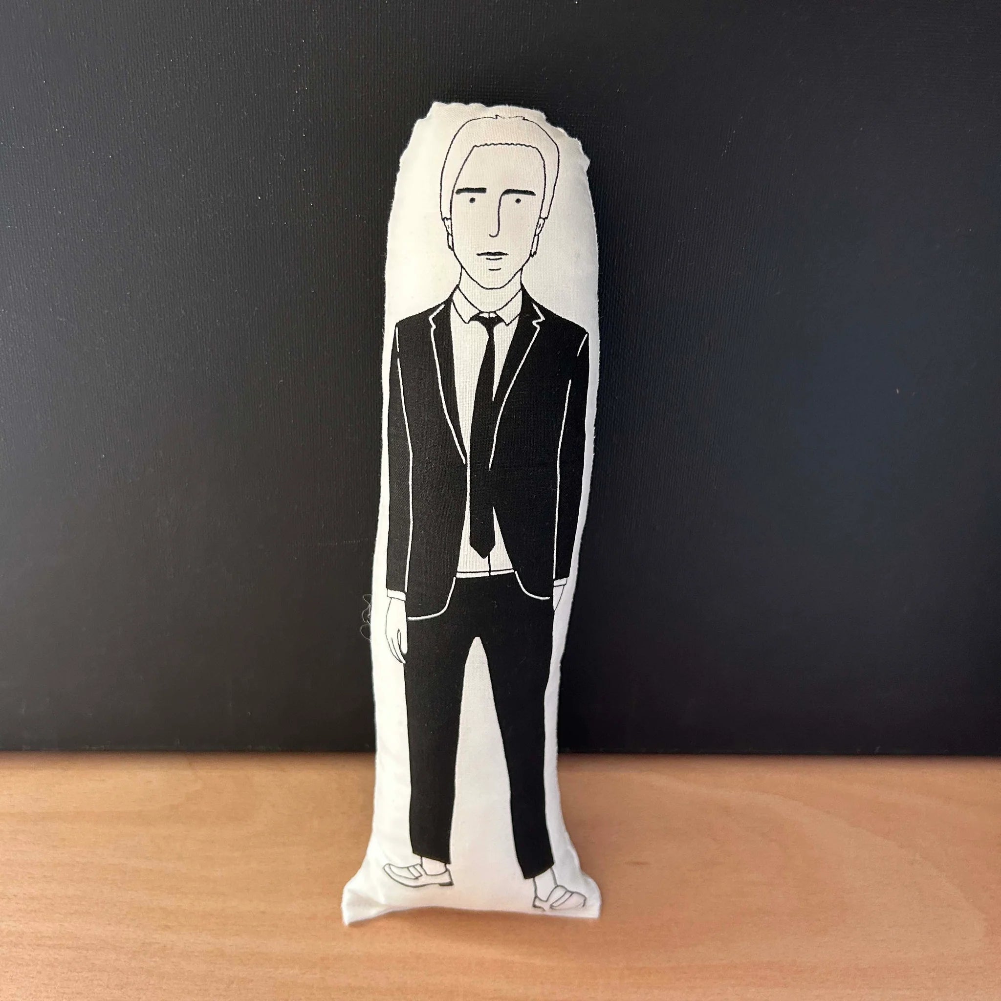 Screen printed doll cushion with white fabric and black illustration depicting Paul Weller weating a black suit