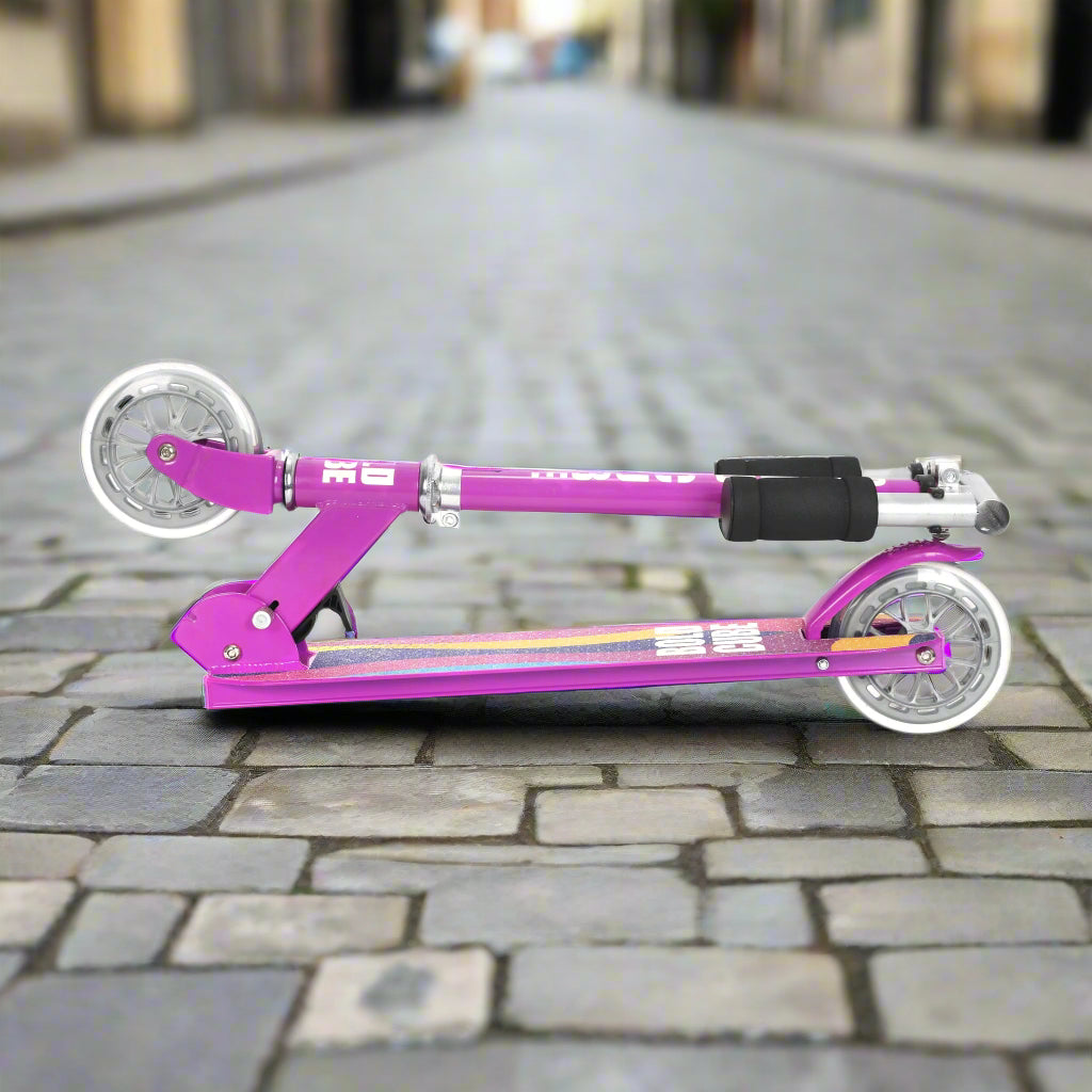 Purple scooter folded into a portable size against a cobbled pavement ackground
