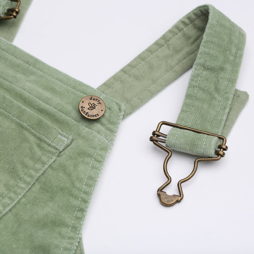 Close up of brass button with bee logo and 'Dotty Dungarees' written on it