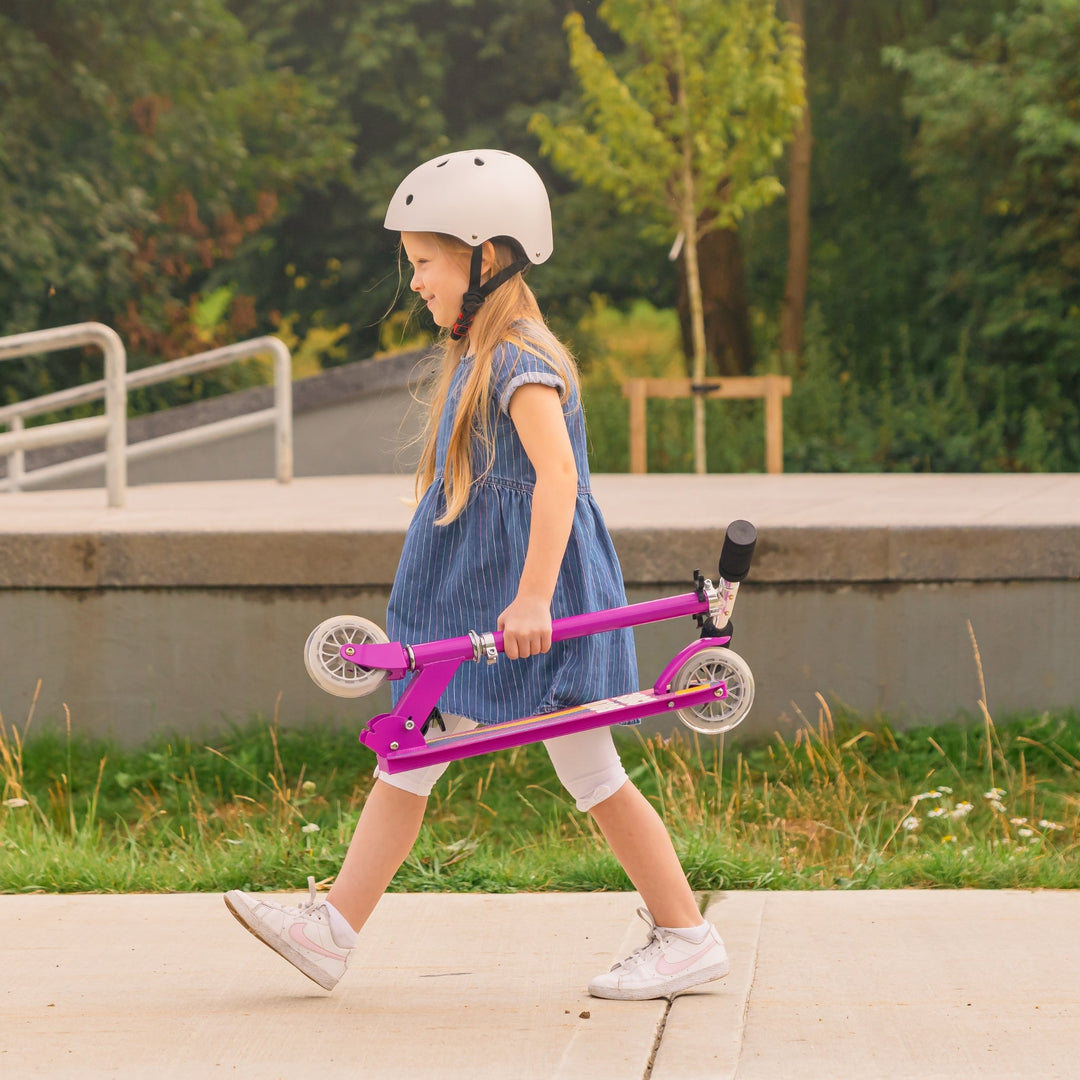 Child walking while carrying the scooter folded into its portable position
