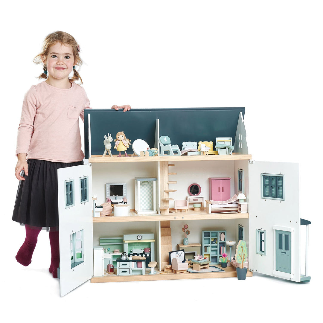 Child with a large dollhouse featuring various rooms and furniture on a white background