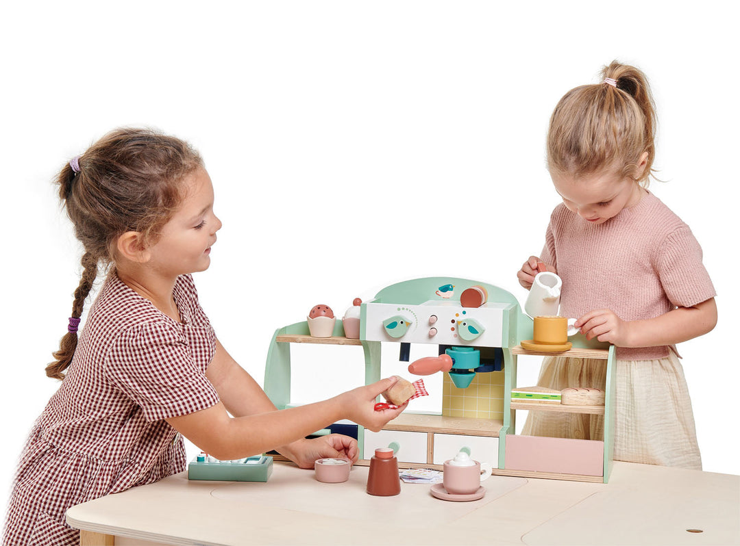 Two children playing with a wooden toy kitchen set on a white background