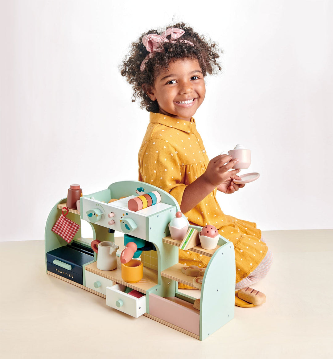 Child playing with a toy cafe set on a white background
