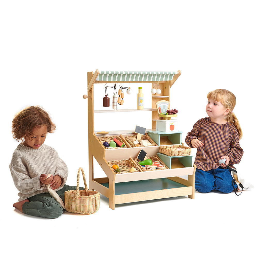 Two children playing with a wooden toy kitchen set on a white background