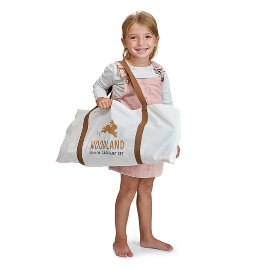 Child holding a large white bag with 'Woodland' branding on a white background