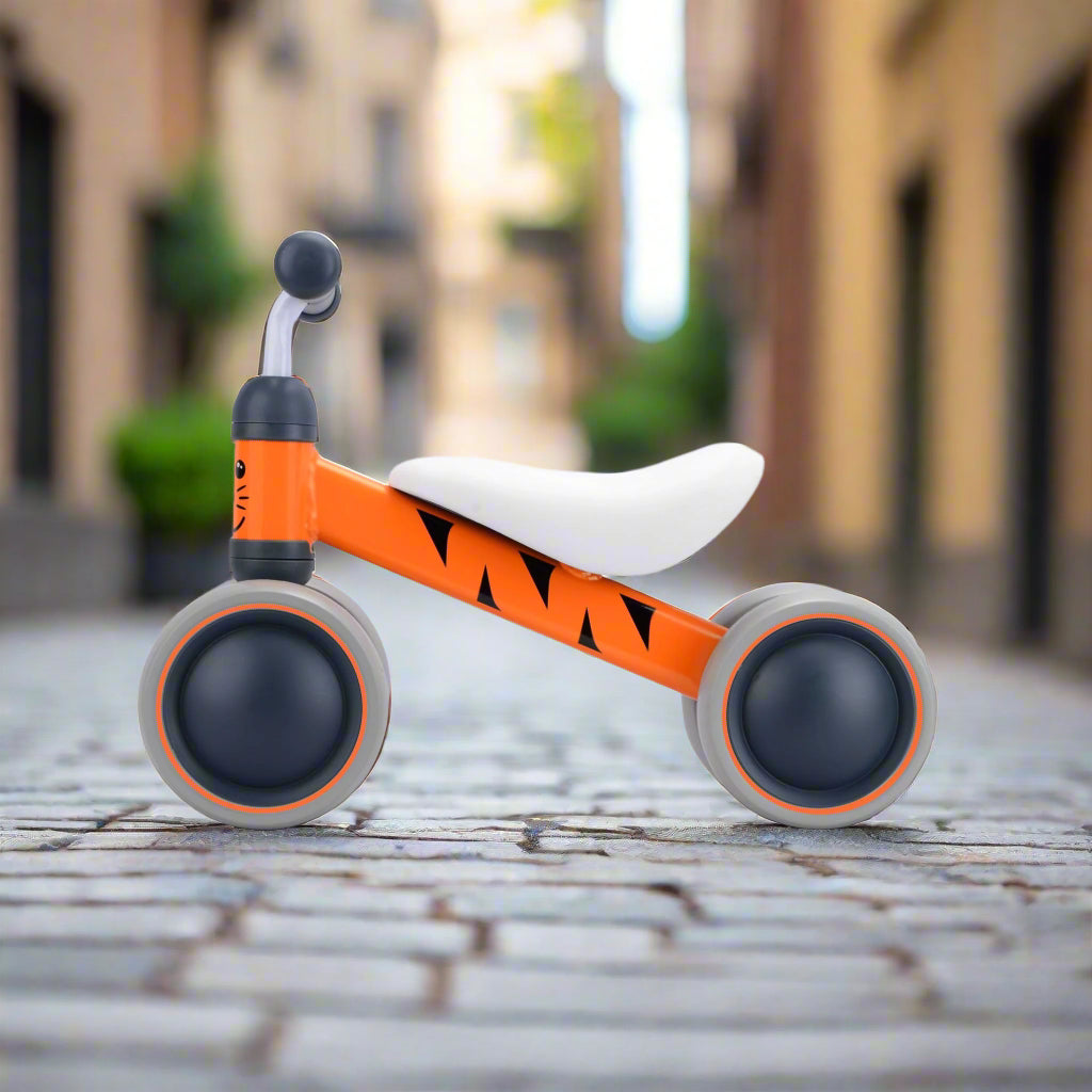 Orange and grey children's balance bike on a cobbled pavement background
