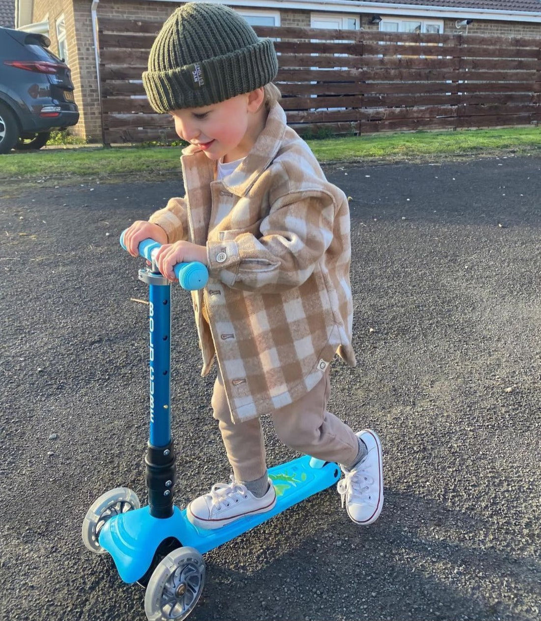 Child riding a blue scooter on a driveway