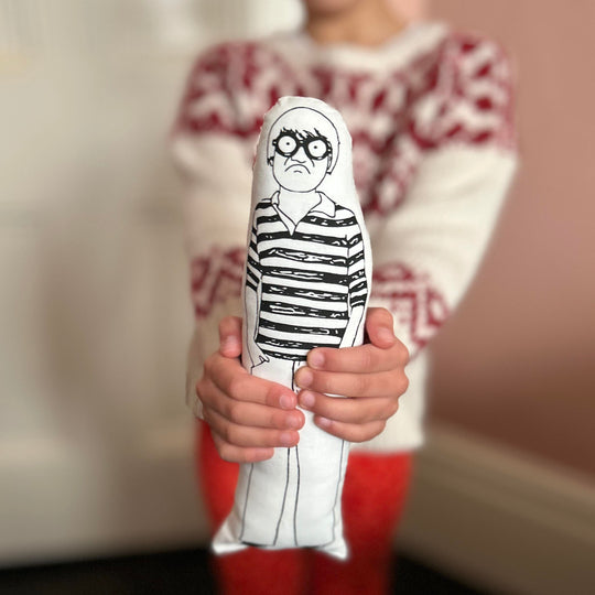 A child holding a screen printed monochrome fabric doll of David Hockney.