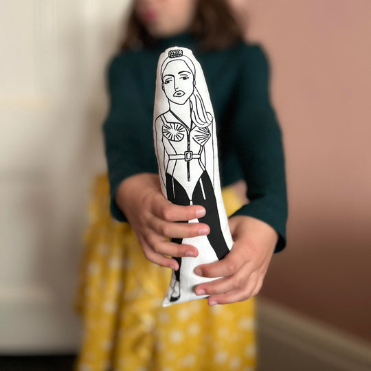 A child holding a black and white screen printed cushion doll with an illustration inspired by Madonna's iconic Gaultier conical bra look.