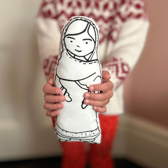 A child holding a black and white screen printed cushion doll of Malala Yousafzai.