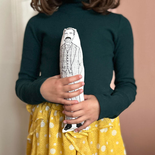 A child holding screen printed doll cushion of fashion deisgner Patrick Grant