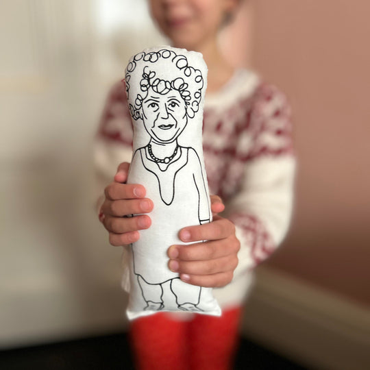 A child holding out the screen printed doll cushion of actor Miriam Margolyes