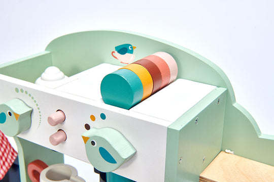 Children's play cafe set with colourful toy pots and bird decorations on a light blue background