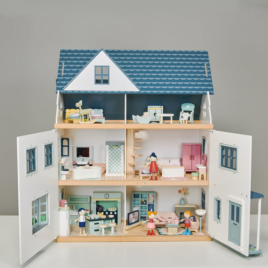 Wooden dollhouse with detailed interior and furniture on a grey background