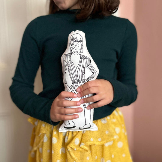 A child holding a black and white screen printed cushion doll of David Bowie