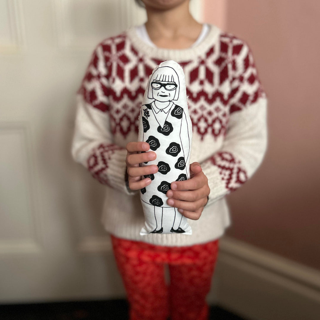A child holding the screen printed doll cushion of fashion deisgned Esme Young