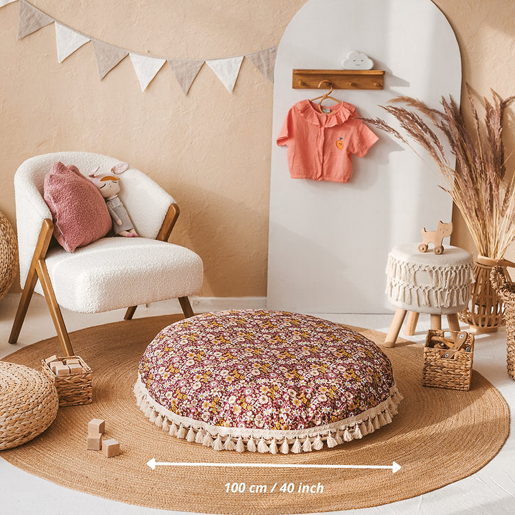 Children's room with floral round cushion, chair, and toys on a beige rug.