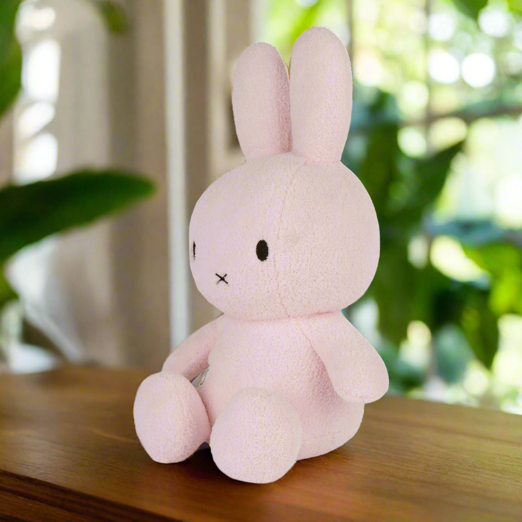 Large pale pink plush stuffed toy rabbit with iconic cross stitched mouth and soft terry fabric