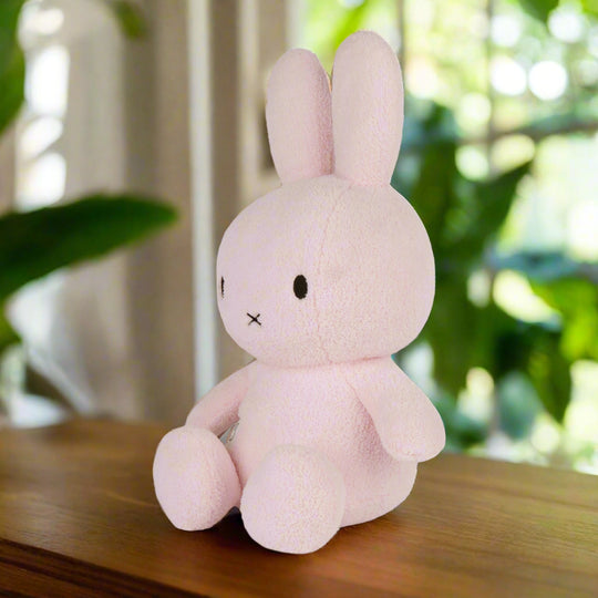 Large pale pink plush stuffed toy rabbit with iconic cross stitched mouth and soft terry fabric