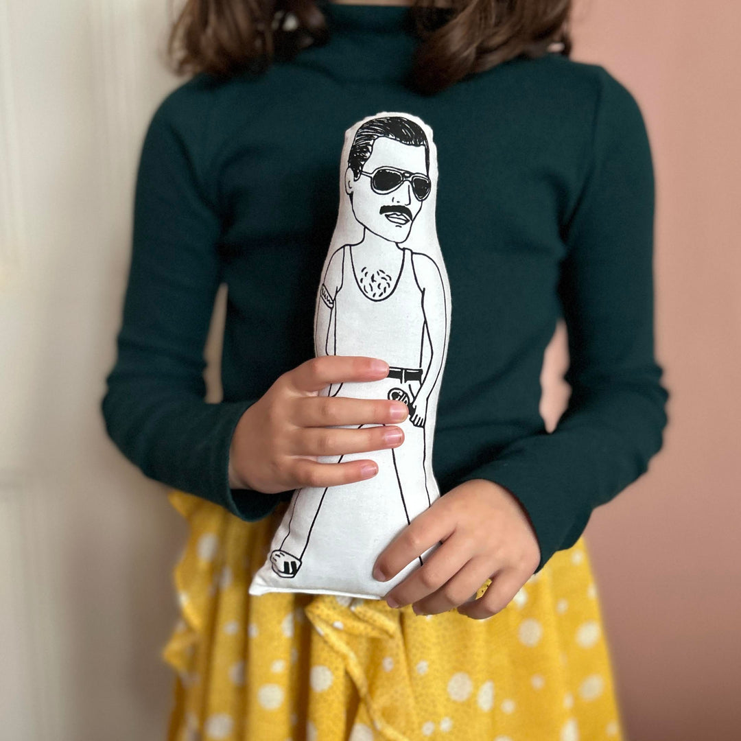 A child holding a screen printed doll cushion of Freddie Mercury