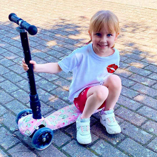 Child sitting on a scooter on a paved surface