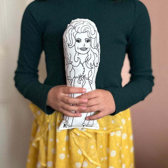 A child holding a screen printed doll of Dolly Parton in both hands