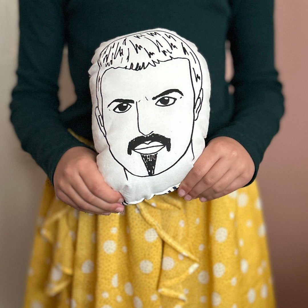 A child holding the screen printed doll cushion of George Michael's face