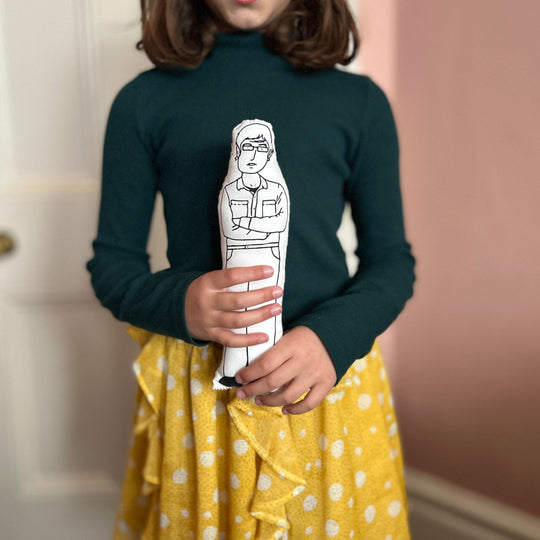 A child stood holding the screen printed doll cushion of Louis Theroux
