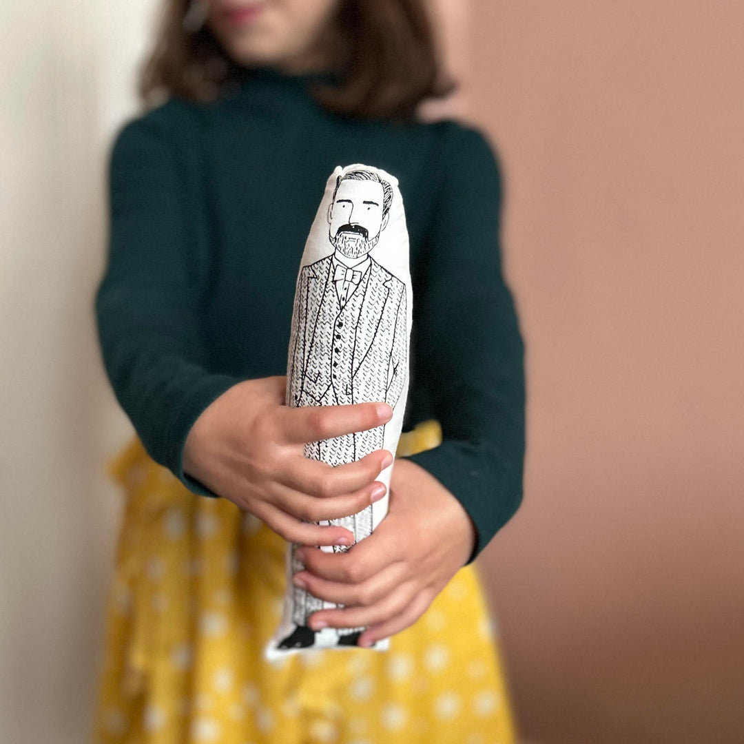 A child holding out cushion doll with a screen printed design of fashion designer Patrick Grant