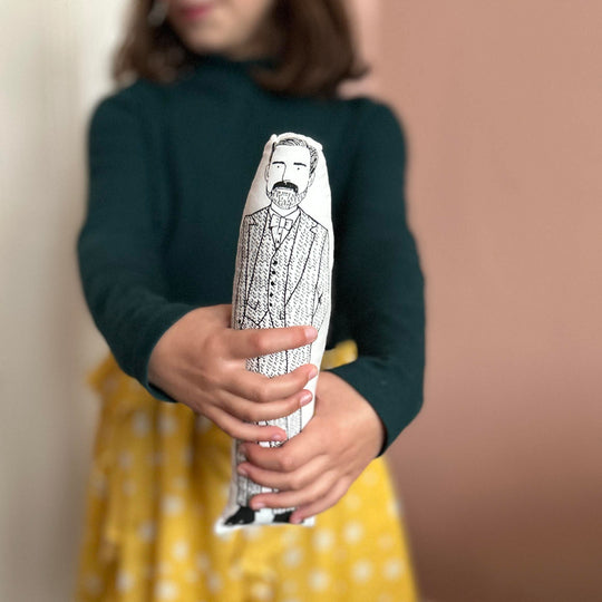 A child holding out cushion doll with a screen printed design of fashion designer Patrick Grant