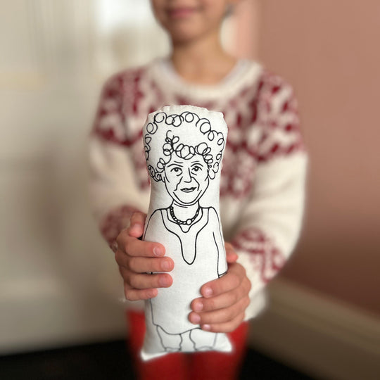 A child holding out the screen printed doll cushion of actor Miriam Margolyes