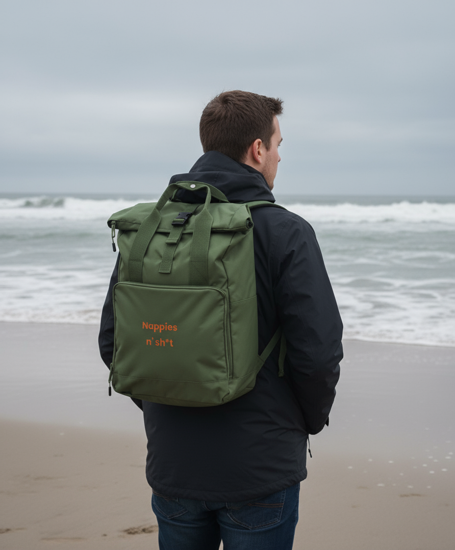 Person wearing a green backpack with 'Nappies n' Sh*t' text on a beach.