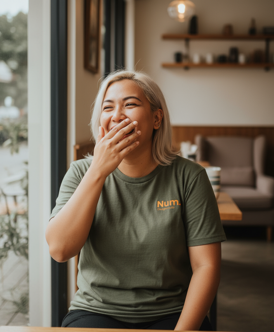 Person wearing a green t-shirt with 'Num' logo indoors