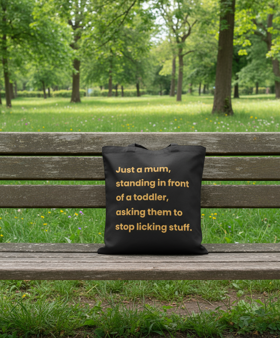 Black tote with yellow text on a wooden bench in a park
