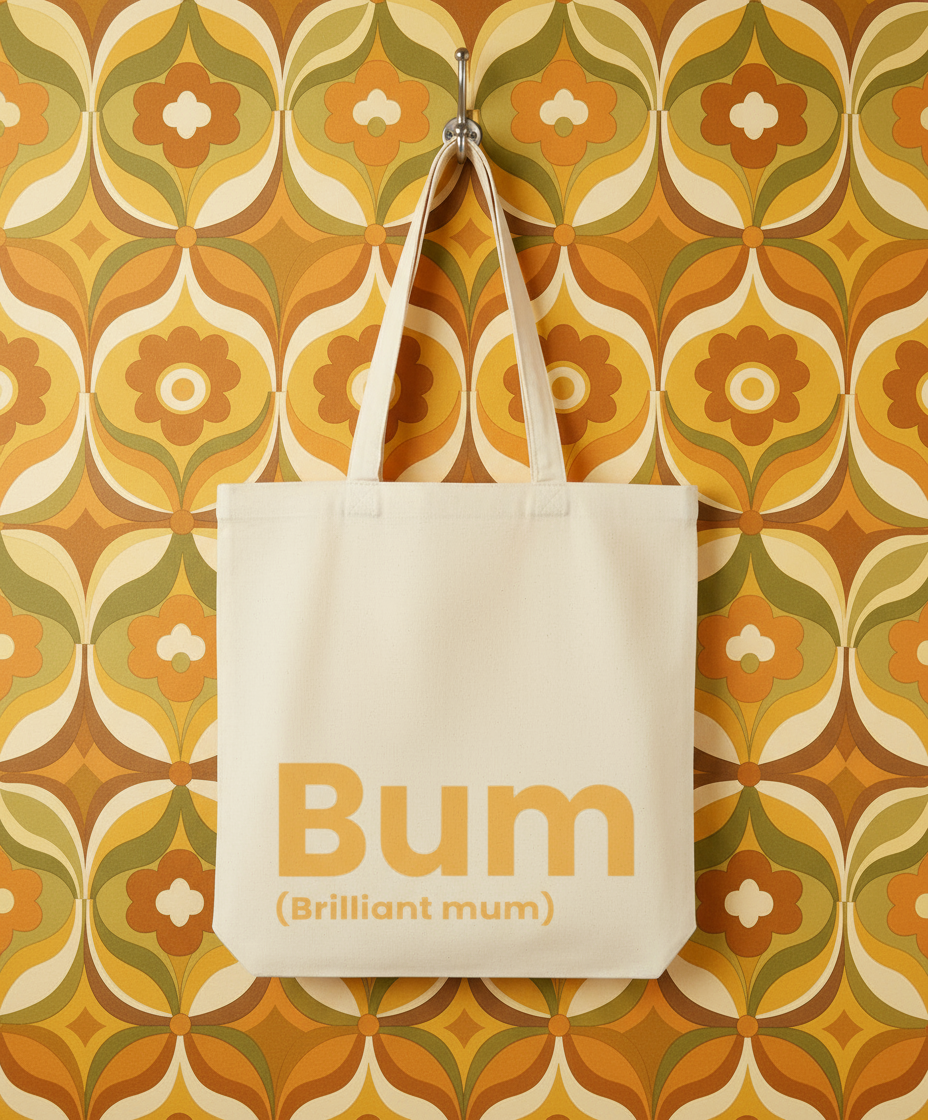 Beige tote bag with 'Bum (Brilliant mum)' text on a patterned wall background