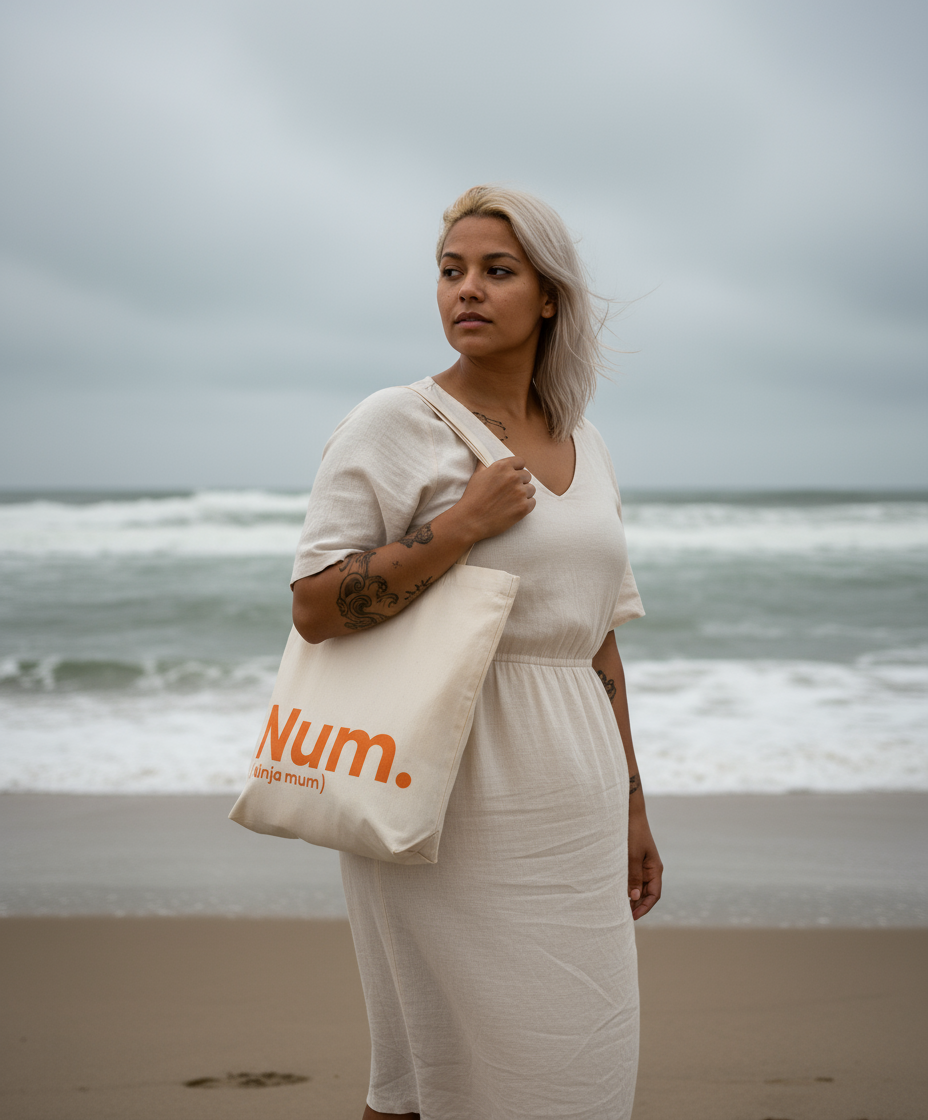 Woman holding a tote bag with 'Num' branding on a beach