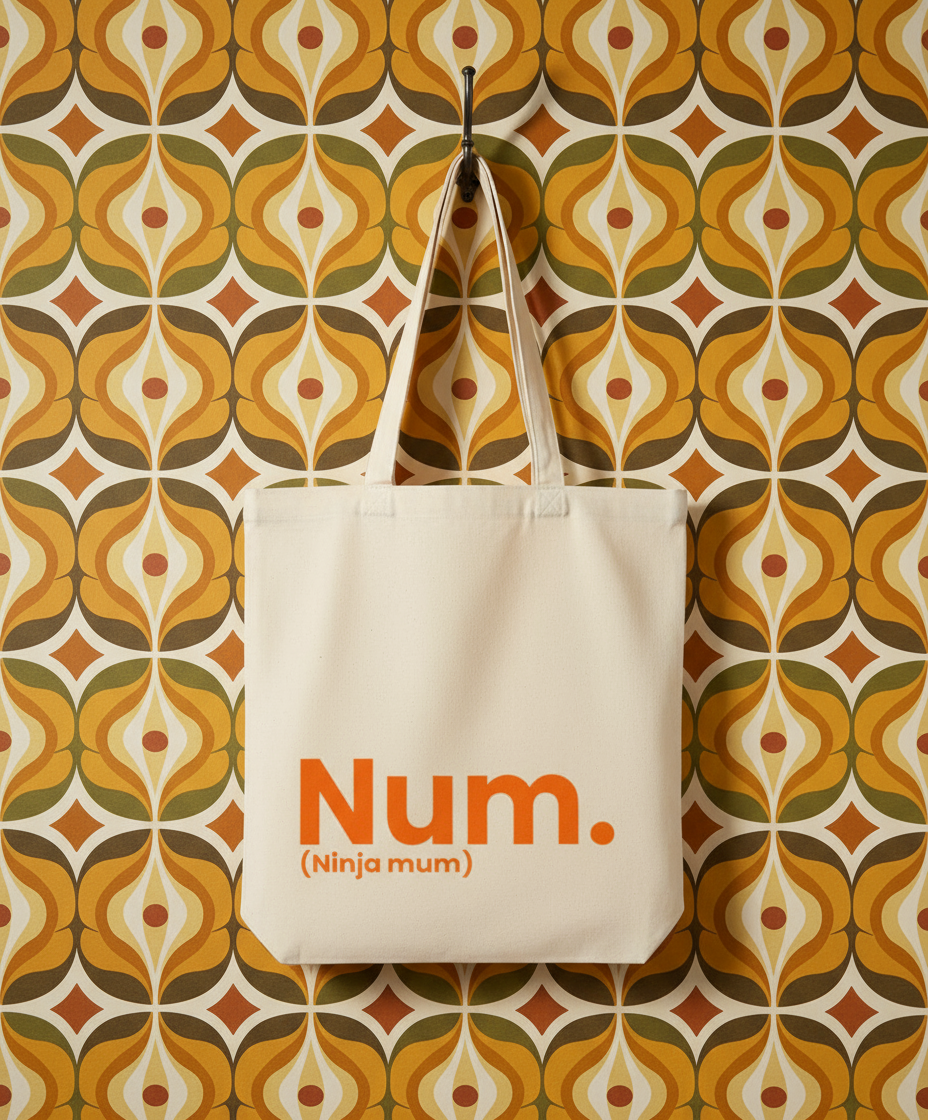 Beige tote bag with 'Num. (Ninja mum)' text on a patterned wall background