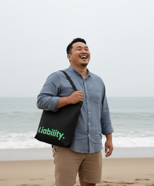 Man holding a black bag with 'Liability' text on a beach