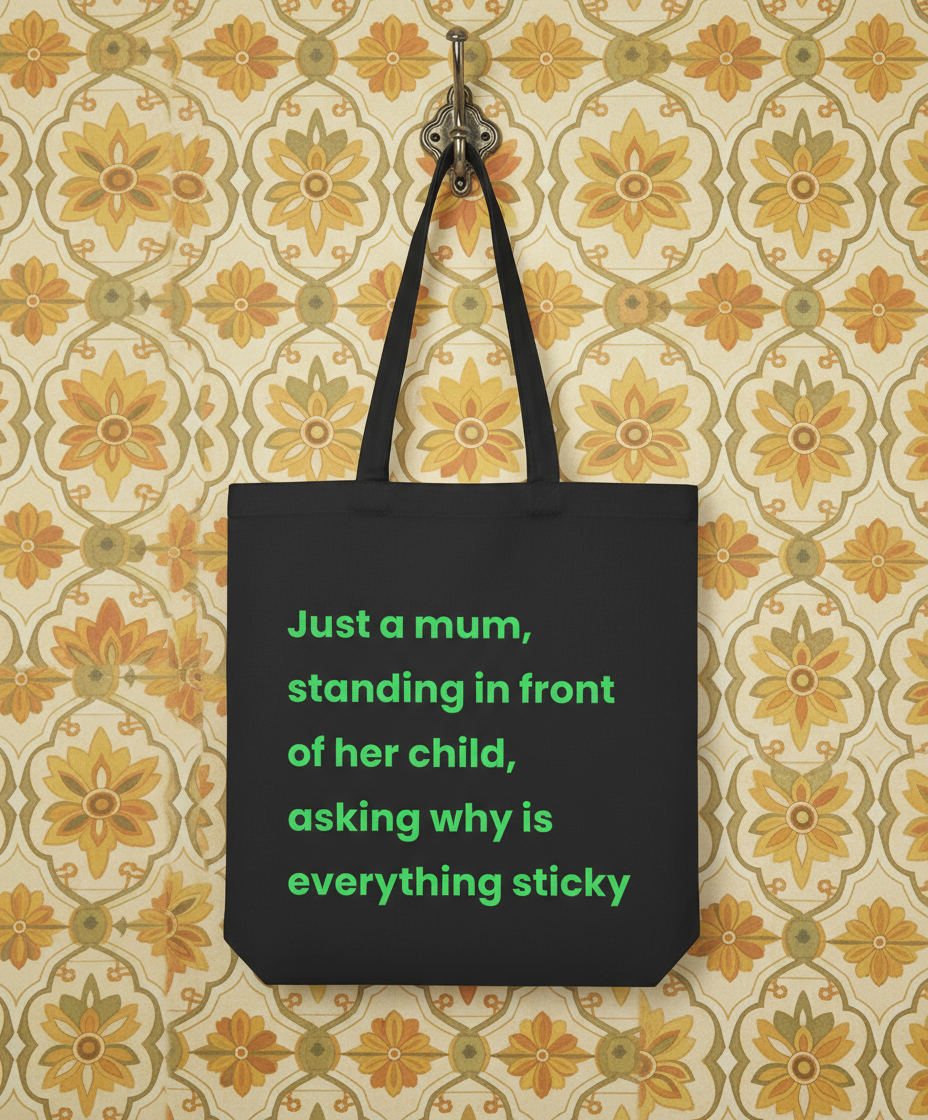 Black tote bag with green text on a floral patterned wall