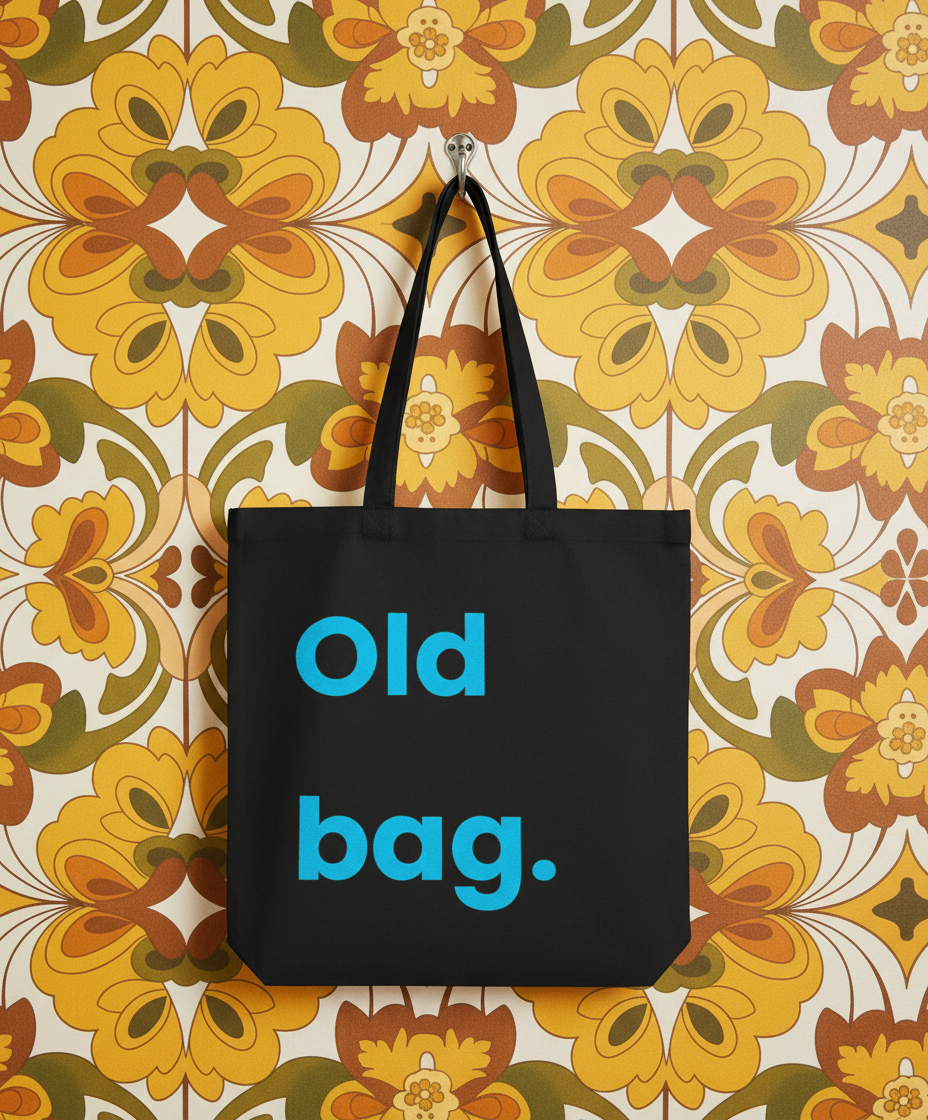 Black tote bag with 'Old bag.' text on a floral-patterned wall.