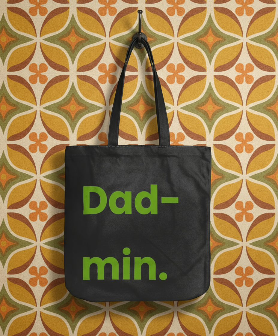 Black tote bag with 'Dad-min.' text on a patterned wall background