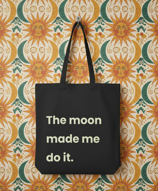 Black tote bag with 'The moon made me do it' text on a sun-patterned background