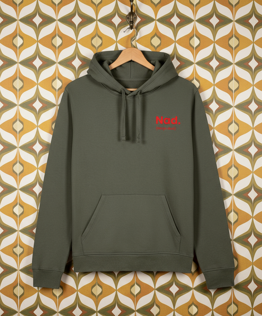 Khaki green hoodie with red text on a hanger against a patterned wall.