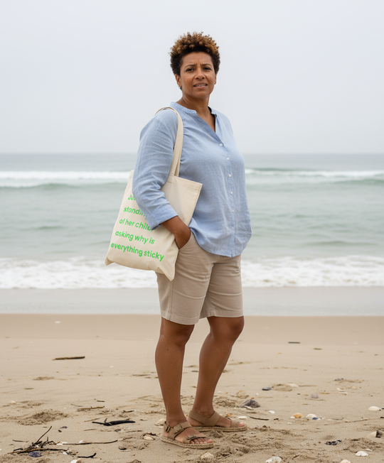 Woman standing on a beach holding a tote bag with text.