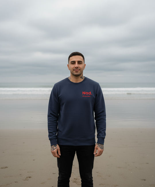 Man wearing a navy blue sweatshirt with red text on a beach