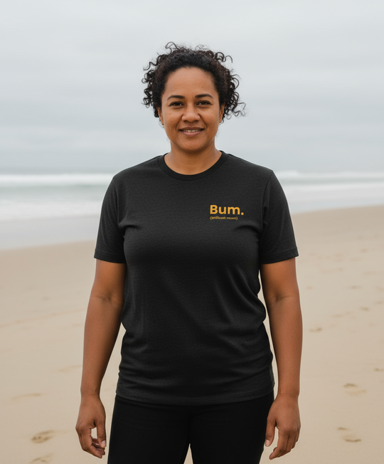 Person wearing a black t-shirt with 'Bum' logo on a beach