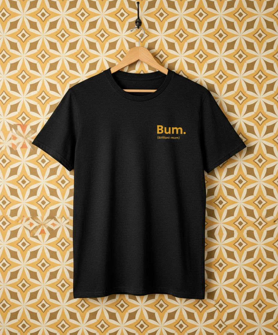 Black t-shirt with 'Bum.' text on a hanger against a patterned wall.