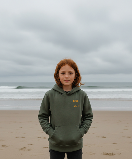 Person wearing a green hoodie with text on a beach