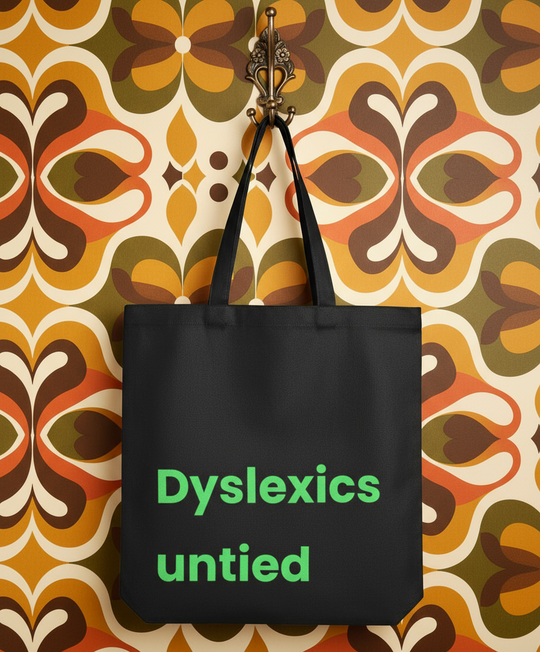 Black tote bag with 'Dyslexics untied' text on a patterned wall background